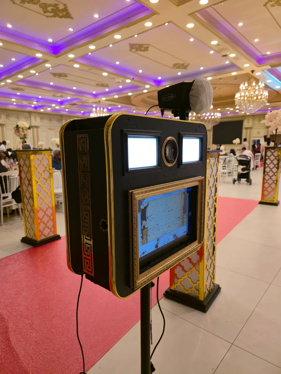 Photobooth noir et doré MySelfieBooth installé sur un tapis rouge dans une salle de réception